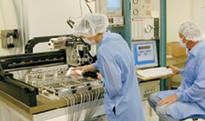 Engineer Dean White (right) and technician Kirsten Affolder operate a gantry robot at the University of California, Santa Barbara, to assemble silicon detector modules for the CMS detector.