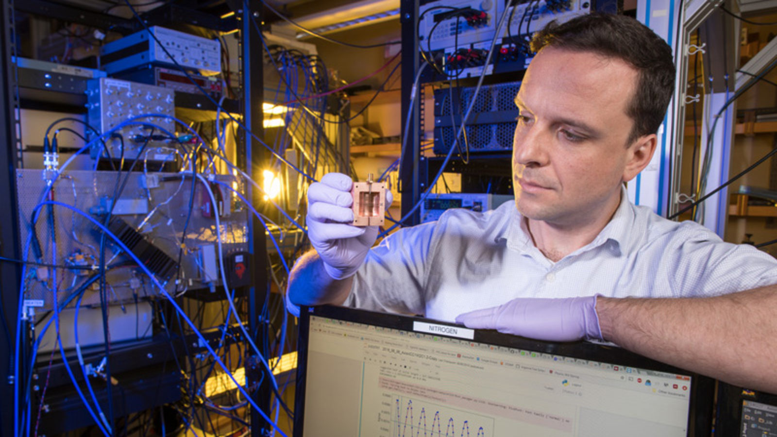 Photo of a scientist holding up a detector component 