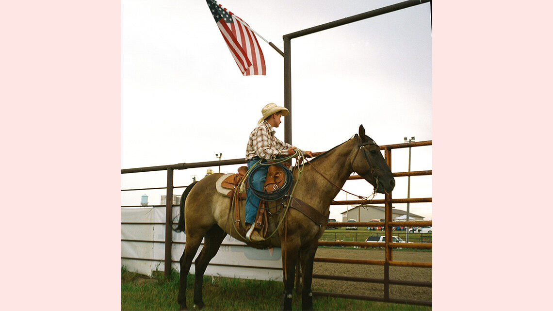 A young man waits on a horse