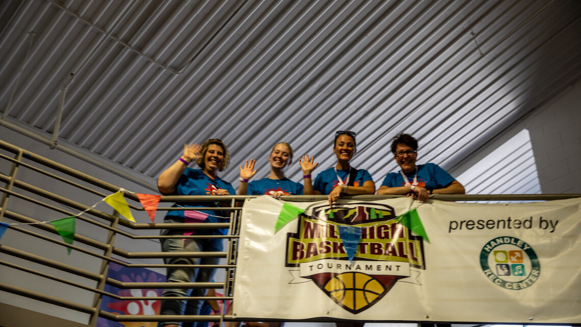 Volunteers at Neutrino Day smile while looking down from a balcony