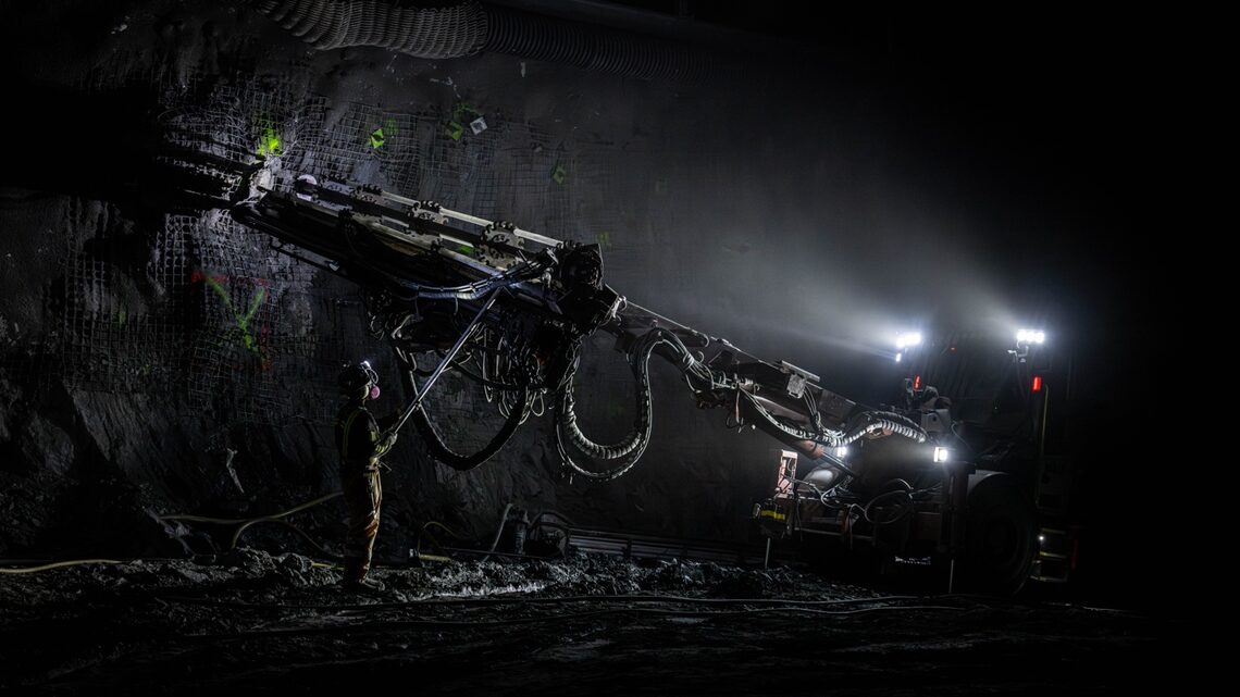 TMI employee next to drilling equipment in a dark cavern