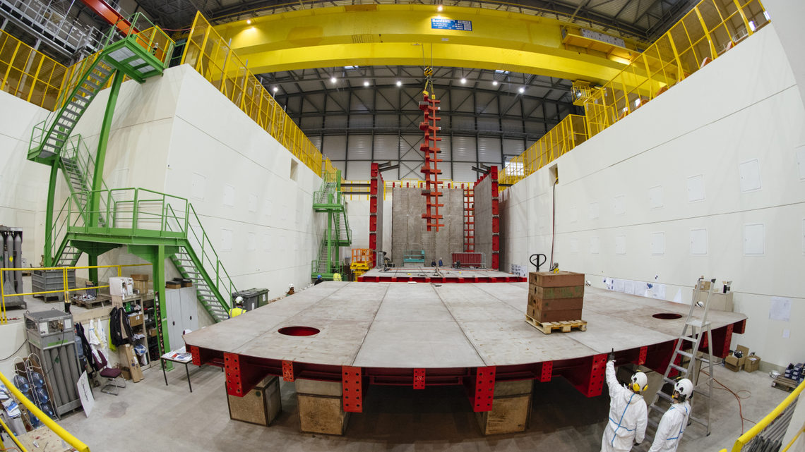 Technicians stand in front of large steel cages