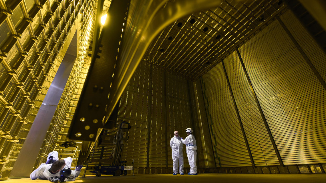 Two technicians stand outside of the field cage