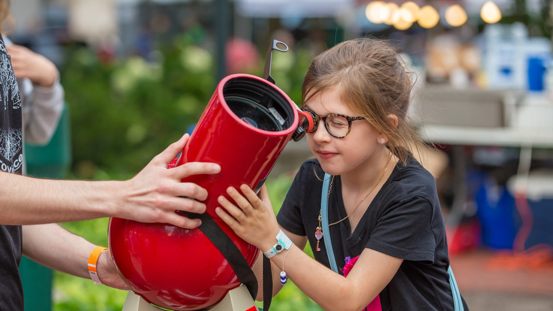 A girl peers through a solar telescope 