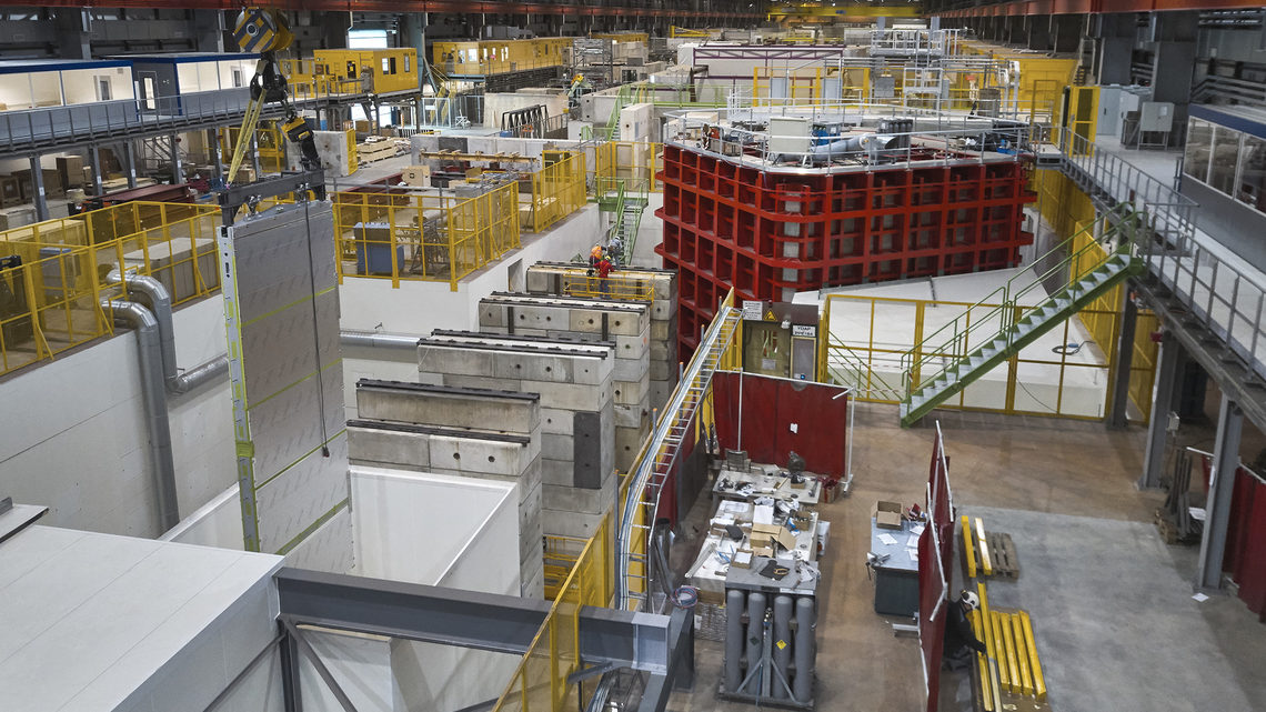 Photo of narrow, wrapped object, the APA, is lifted by a crane