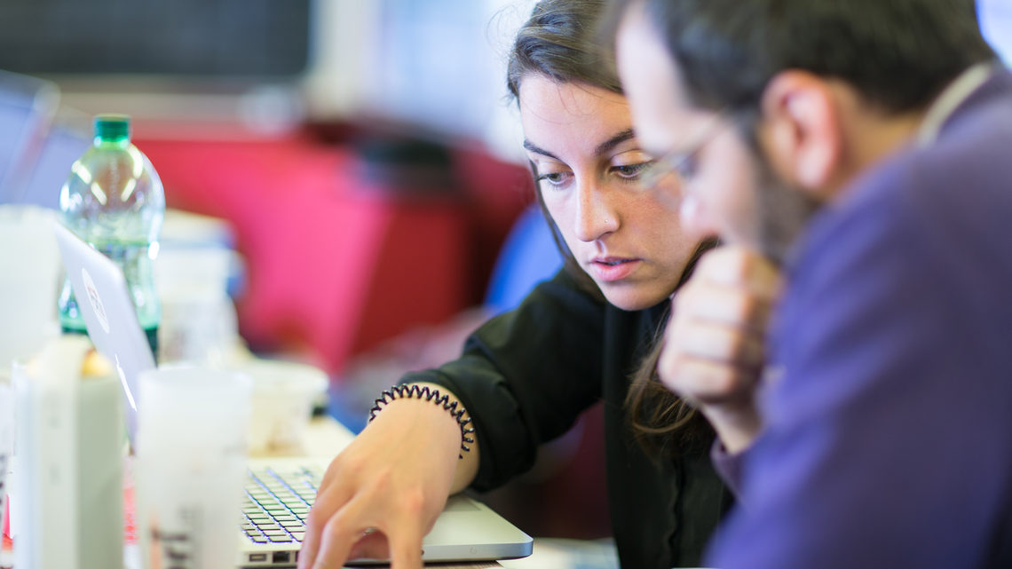 Image of two people working on a computer 