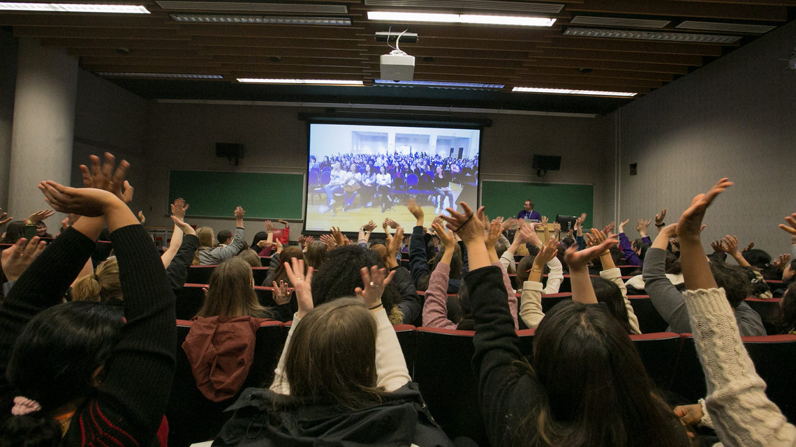Photo before the beginning of the shared video keynote talk, attendees at each CUWiP site cheer and wave on video