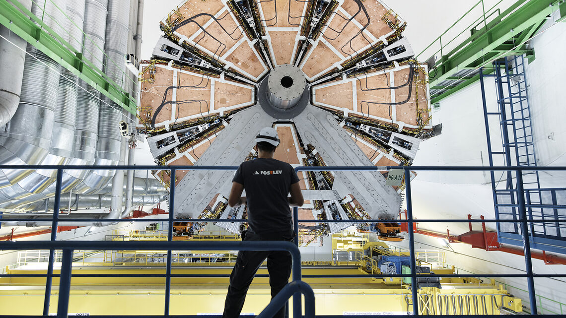 Photo of a person, facing away, standing by a railing next to a mutli-story detector component