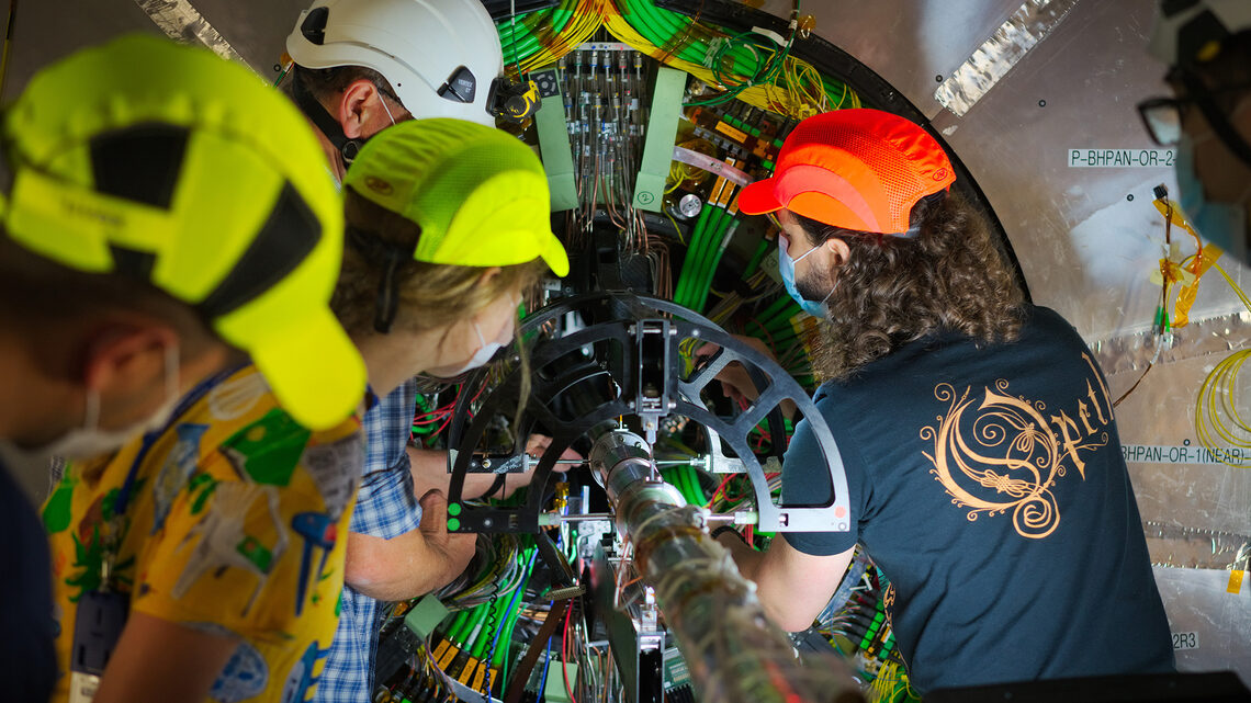 Photo of four people working on a detector component
