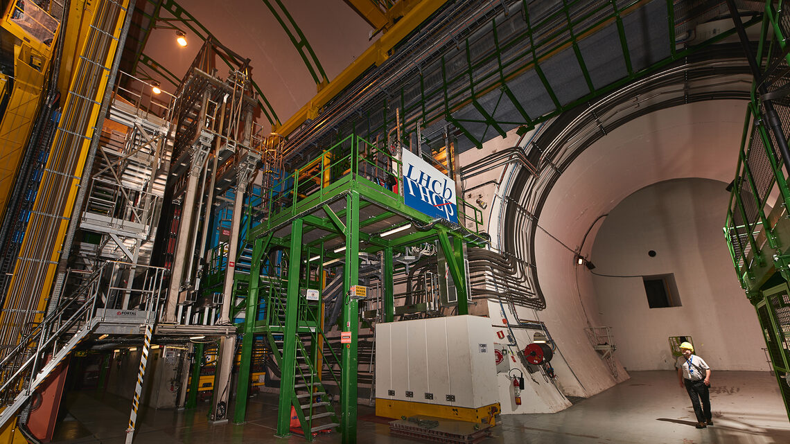 Photo of a person in a hard hat walking into a cavern with the logo for the LHCb experiment