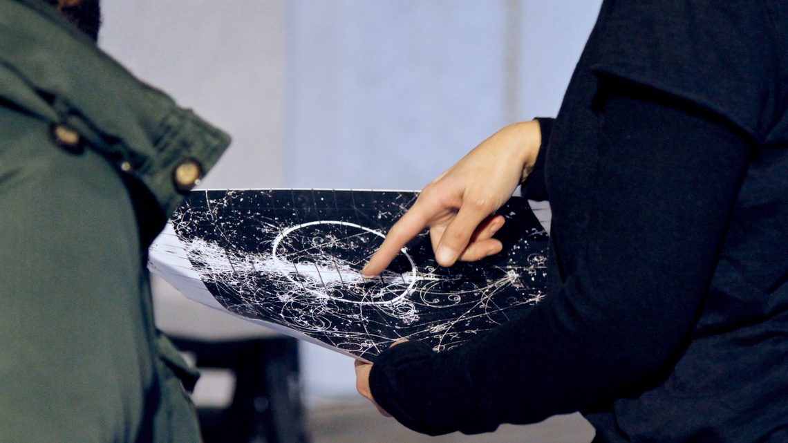 Photo of a hand pointing to the original bubble chamber image