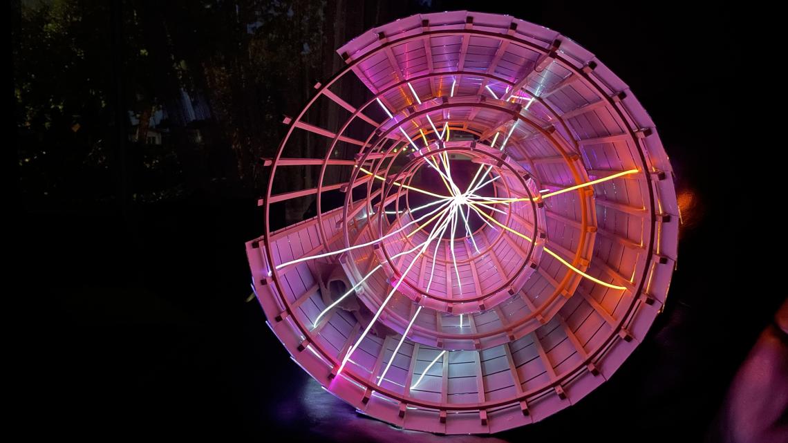 Photograph of the Disco-tracker, seen from the end so that all three cylinders are visible, with its wires glowing in the dark