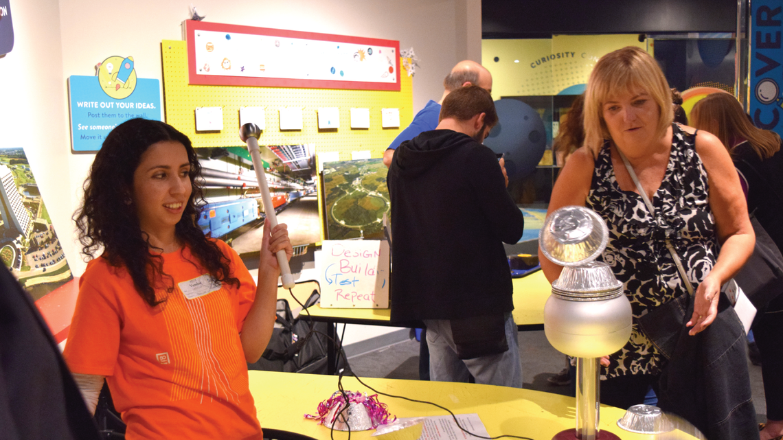 Photo of a volunteer demonstrating magnetism at a Dark Matter Day event at Adler Planetarium in Chicago