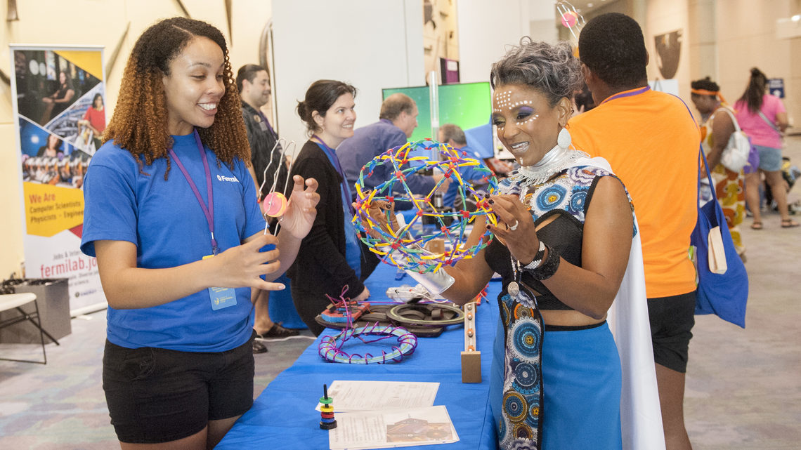 A Wakandacon attendee in costume visits the Fermilab booth