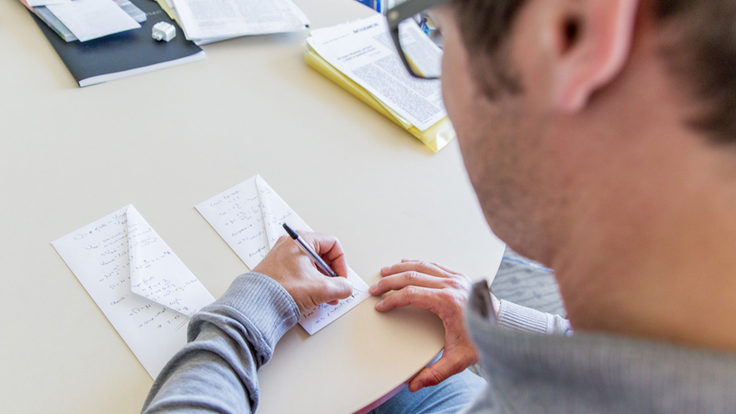 Photo of man writing on back of the envelopes