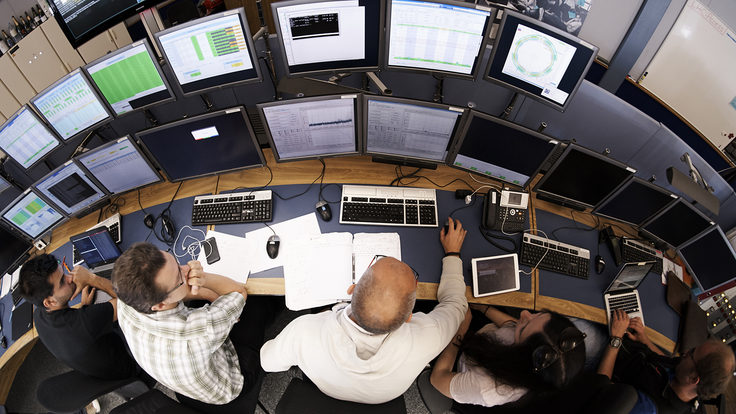 Overhead view of people sitting in front of two rows of computer screens