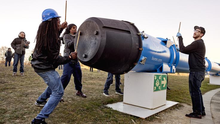 STOMP performers drum on a retired LHC cavity