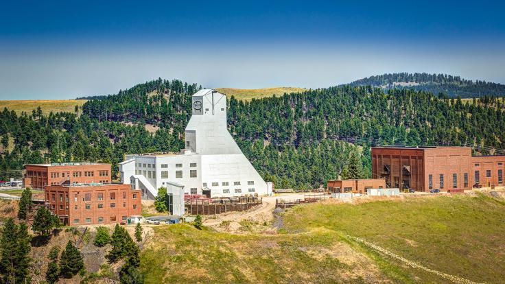 Photo of the Yates surface facilities at Sanford Lab, a white building surrounded by tree-covered mountains
