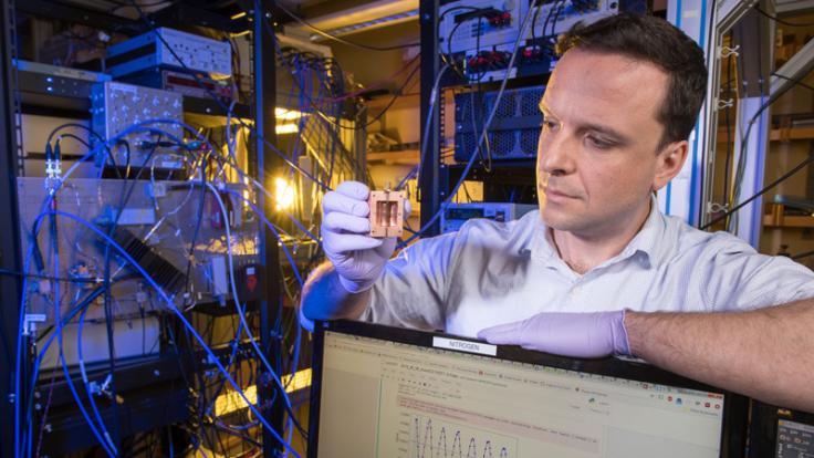 Photo of a scientist holding up a detector component 