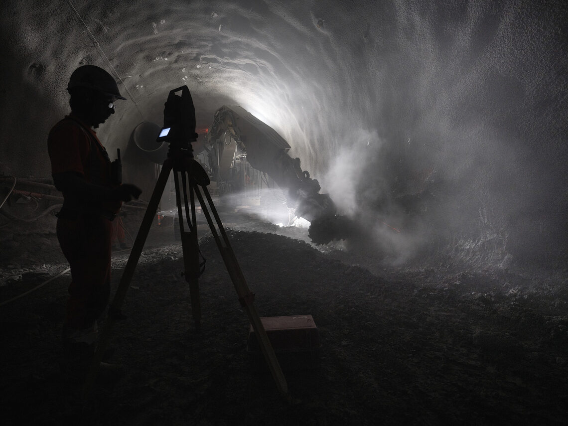 Silhouette of person in construction helmet in dimly lit tunnel