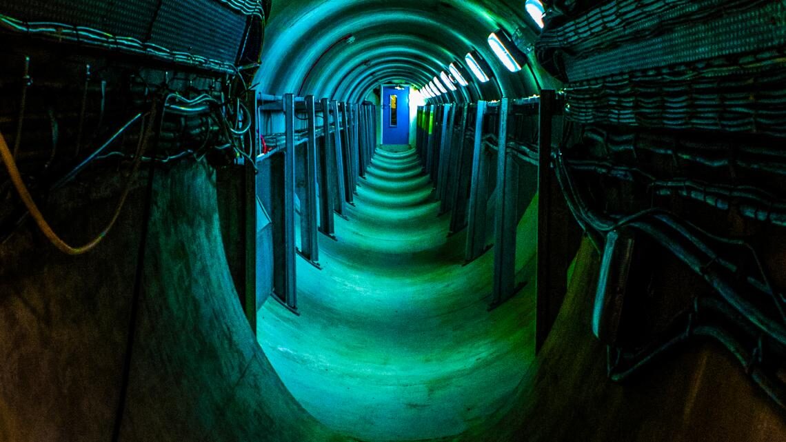 Photo looking through a green-hued tunnel with a blue door at the end